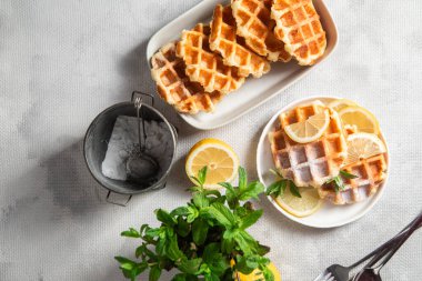 Masadaki beyaz tabakta naneli ve limonlu süzme peynirden yapılmış Belçika waffleları. Sağlıklı kahvaltı.