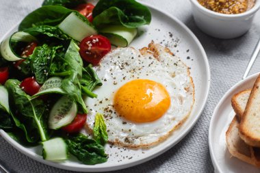 Beyaz tabakta ıspanaklı yumurta, domates ve salatalık salatası. Sağlıklı kahvaltı.