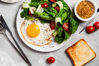 Beyaz tabakta ıspanaklı yumurta, domates ve salatalık salatası. Sağlıklı kahvaltı.