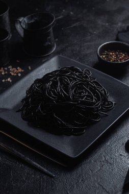 Siyah bir tabakta siyah bir arka planda siyah spagetti. Mürekkep balıklı siyah macun.