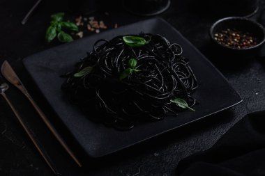Siyah bir tabakta siyah bir arka planda siyah spagetti. Mürekkep balıklı siyah macun.