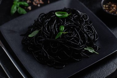 Siyah bir tabakta siyah bir arka planda siyah spagetti. Mürekkep balıklı siyah macun.