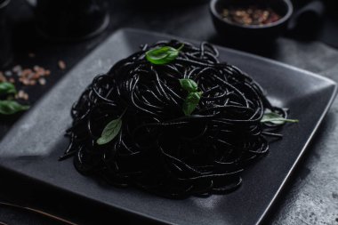 Siyah bir tabakta siyah bir arka planda siyah spagetti. Mürekkep balıklı siyah macun.