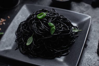 Siyah bir tabakta siyah bir arka planda siyah spagetti. Mürekkep balıklı siyah macun.