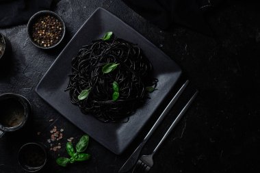 Siyah bir tabakta siyah bir arka planda siyah spagetti. Mürekkep balıklı siyah macun.