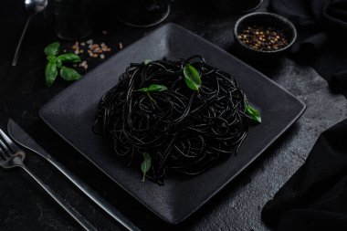 Siyah bir tabakta siyah bir arka planda siyah spagetti. Mürekkep balıklı siyah macun.