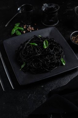 Siyah bir tabakta siyah bir arka planda siyah spagetti. Mürekkep balıklı siyah macun.