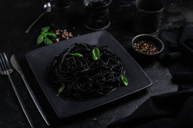 Siyah bir tabakta siyah bir arka planda siyah spagetti. Mürekkep balıklı siyah macun.