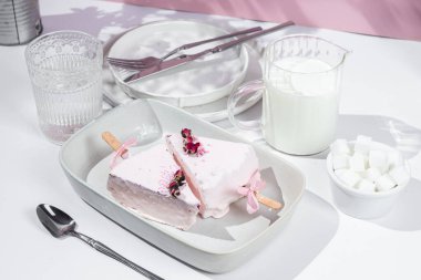 Masadaki beyaz tabakta peynirli kek. Cilalı cheesecake. Tatlı.