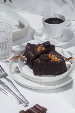 Masadaki beyaz tabakta çubuk üzerinde cheesecake. Cilalı cheesecake. Tatlı.