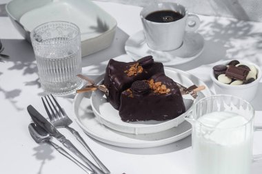 Masadaki beyaz tabakta çubuk üzerinde cheesecake. Cilalı cheesecake. Tatlı.