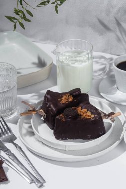 Masadaki beyaz tabakta çubuk üzerinde cheesecake. Cilalı cheesecake. Tatlı.