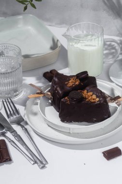 Masadaki beyaz tabakta çubuk üzerinde cheesecake. Cilalı cheesecake. Tatlı.