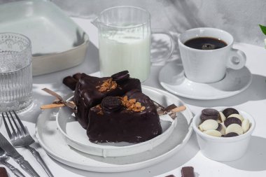 Masadaki beyaz tabakta çubuk üzerinde cheesecake. Cilalı cheesecake. Tatlı.