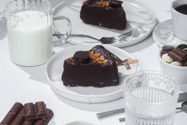 Masadaki beyaz tabakta çubuk üzerinde cheesecake. Cilalı cheesecake. Tatlı.