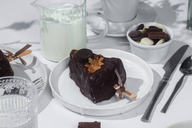 Masadaki beyaz tabakta çubuk üzerinde cheesecake. Cilalı cheesecake. Tatlı.