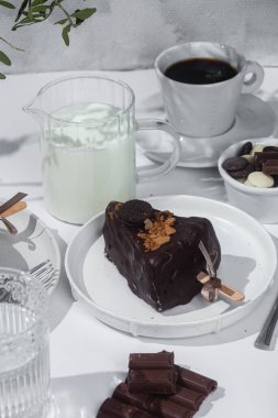 Masadaki beyaz tabakta çubuk üzerinde cheesecake. Cilalı cheesecake. Tatlı.