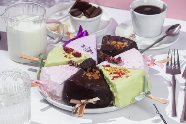 Masadaki beyaz tabakta çubuk üzerinde cheesecake. Cilalı cheesecake. Tatlı.