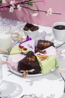 Masadaki beyaz tabakta çubuk üzerinde cheesecake. Cilalı cheesecake. Tatlı.