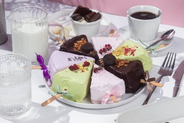 Masadaki beyaz tabakta çubuk üzerinde cheesecake. Cilalı cheesecake. Tatlı.