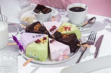 Masadaki beyaz tabakta çubuk üzerinde cheesecake. Cilalı cheesecake. Tatlı.