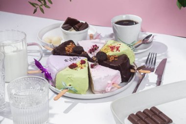 Masadaki beyaz tabakta çubuk üzerinde cheesecake. Cilalı cheesecake. Tatlı.