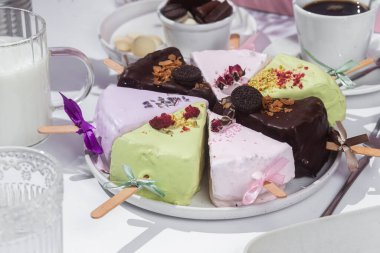 Masadaki beyaz tabakta çubuk üzerinde cheesecake. Cilalı cheesecake. Tatlı.