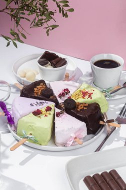 Masadaki beyaz tabakta çubuk üzerinde cheesecake. Cilalı cheesecake. Tatlı.