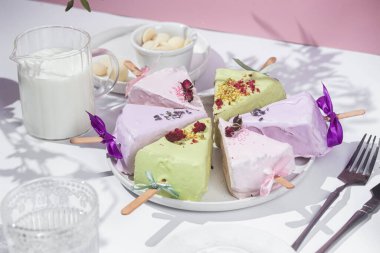 Masadaki beyaz tabakta çubuk üzerinde cheesecake. Cilalı cheesecake. Tatlı.