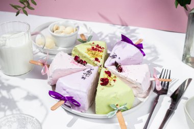 Masadaki beyaz tabakta çubuk üzerinde cheesecake. Cilalı cheesecake. Tatlı.