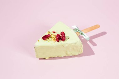 Masadaki beyaz tabakta çubuk üzerinde cheesecake. Cilalı cheesecake. Tatlı.