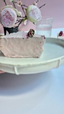 Masadaki beyaz tabakta çubuk üzerinde cheesecake. Cilalı cheesecake. Tatlı.