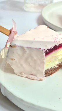 Masadaki beyaz tabakta çubuk üzerinde cheesecake. Cilalı cheesecake. Tatlı.