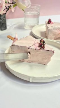 Masadaki beyaz tabakta çubuk üzerinde cheesecake. Cilalı cheesecake. Tatlı.