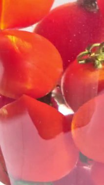 Suda hareketli kiraz domatesleri açık arkaplanda yakın plan