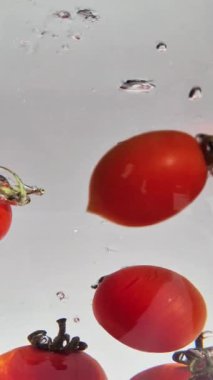 Suda hareketli kiraz domatesleri açık arkaplanda yakın plan