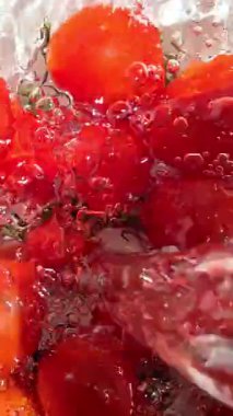 Suda hareketli kiraz domatesleri açık arkaplanda yakın plan