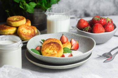 Syrniki Cheesecakes krem soslu süzme peynirli krep, çilek ve nane şekeri tabakta. Kahvaltı.