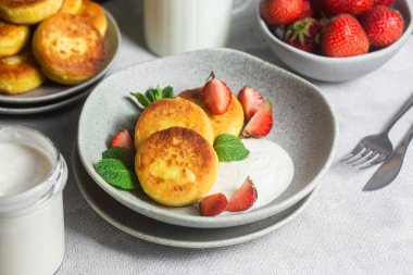 Syrniki Cheesecakes krem soslu süzme peynirli krep, çilek ve nane şekeri tabakta. Kahvaltı.