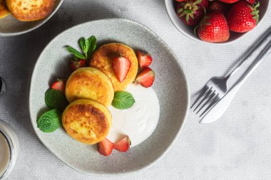 Syrniki Cheesecakes krem soslu süzme peynirli krep, çilek ve nane şekeri tabakta. Kahvaltı.