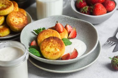 Syrniki Cheesecakes krem soslu süzme peynirli krep, çilek ve nane şekeri tabakta. Kahvaltı.