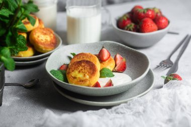 Syrniki Cheesecakes krem soslu süzme peynirli krep, çilek ve nane şekeri tabakta. Kahvaltı.