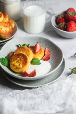 Syrniki Cheesecakes krem soslu süzme peynirli krep, çilek ve nane şekeri tabakta. Kahvaltı.