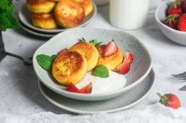 Syrniki Cheesecakes krem soslu süzme peynirli krep, çilek ve nane şekeri tabakta. Kahvaltı.