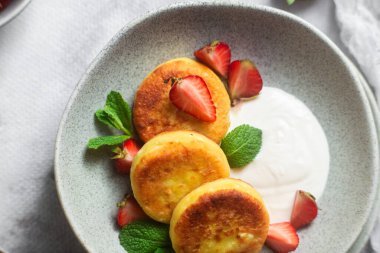 Syrniki Cheesecakes krem soslu süzme peynirli krep, çilek ve nane şekeri tabakta. Kahvaltı.