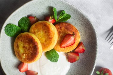 Syrniki Cheesecakes krem soslu süzme peynirli krep, çilek ve nane şekeri tabakta. Kahvaltı.