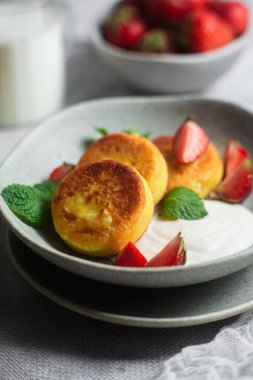 Syrniki Cheesecakes krem soslu süzme peynirli krep, çilek ve nane şekeri tabakta. Kahvaltı.