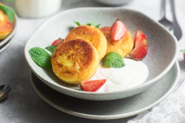 Syrniki Cheesecakes krem soslu süzme peynirli krep, çilek ve nane şekeri tabakta. Kahvaltı.