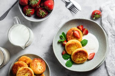 Syrniki Cheesecakes krem soslu süzme peynirli krep, çilek ve nane şekeri tabakta. Kahvaltı.