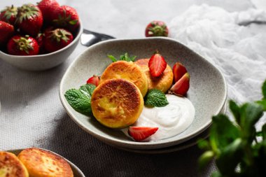 Syrniki Cheesecakes krem soslu süzme peynirli krep, çilek ve nane şekeri tabakta. Kahvaltı.